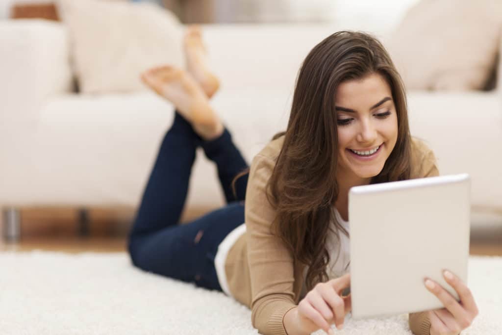 attractive woman on carpet using digital tablet WV2B6LX 1024x683 1