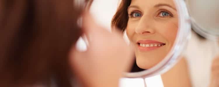 woman smiling and looking in mirror