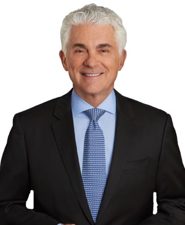 Headshot of Doctor in suit smiling against solid white background